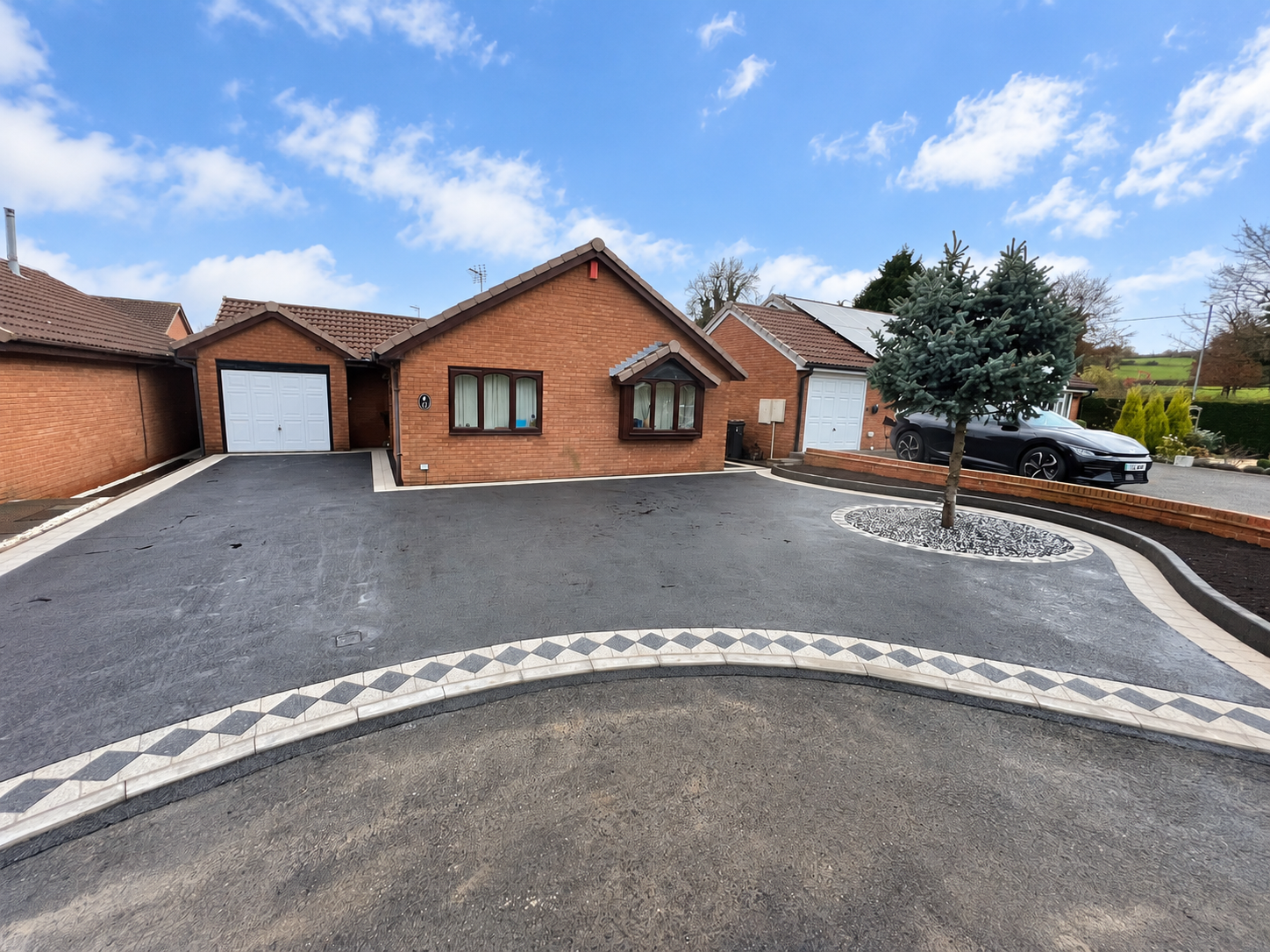 Tarmac driveway with diamond-pattern block paving and curved edging by A Griggs Driveways